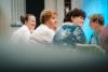 grupa kobiet siedząca przy stole uśmiechnięta, patrzące w jedną stronę